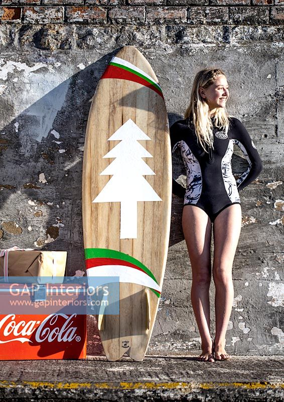 Surfer leaning on wall with cool box and wrapped gift