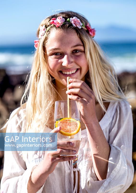 Young woman drinking a drink at the beach 