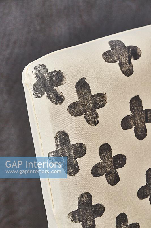 Black crosses on white fabric slipcover on chair 