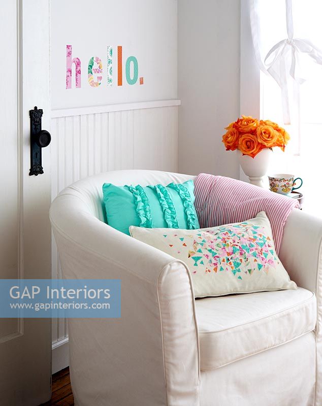 Upholstered armchair with colourful cut out fabric word on wall 
