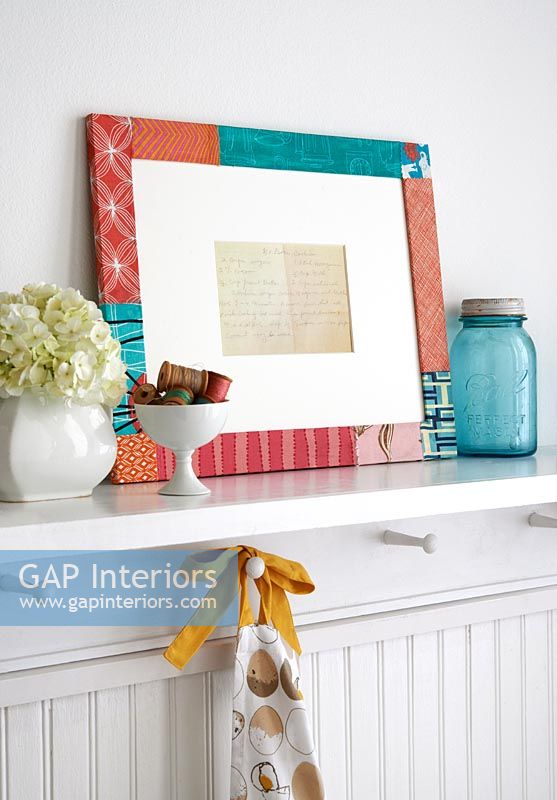 Colourful fabric covered picture frame on shelf 