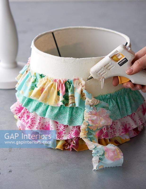 Decorating lampshade using fabric strips and a glue gun 
