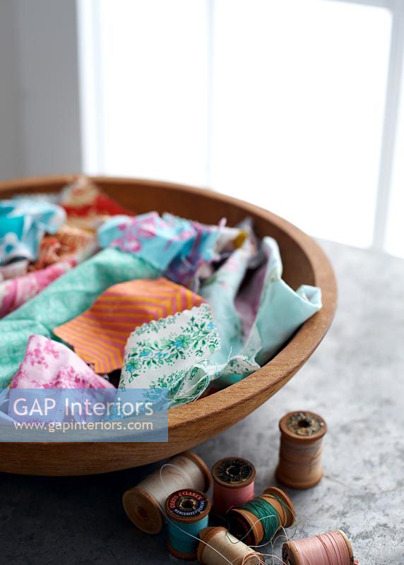 Bowl of colourful fabric cuttings and cotton reels 