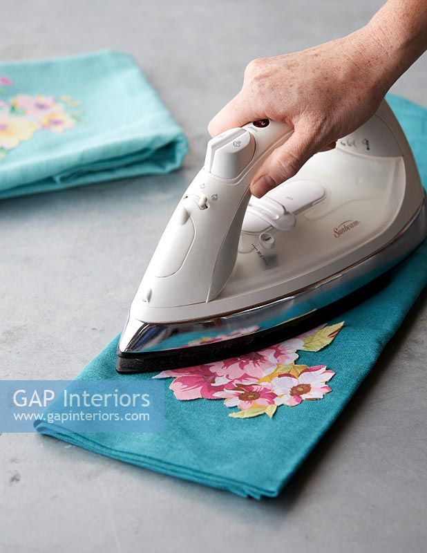 Pressing a cut out floral fabric onto another larger piece 