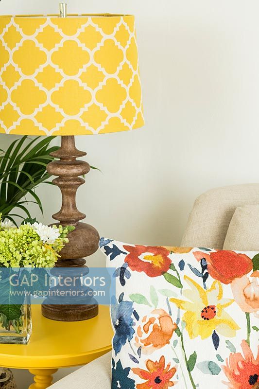 Colourful floral cushion and yellow patterned lampshade 