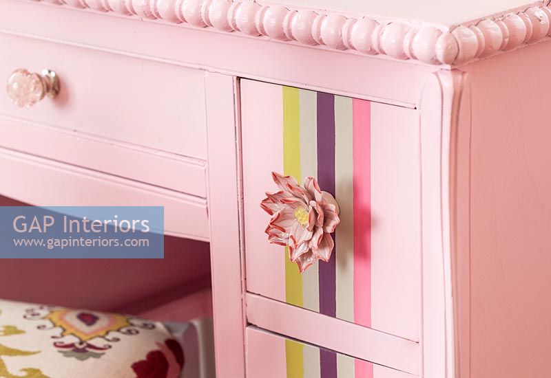 Pink flowers door knobs on colourful painted dressing table 