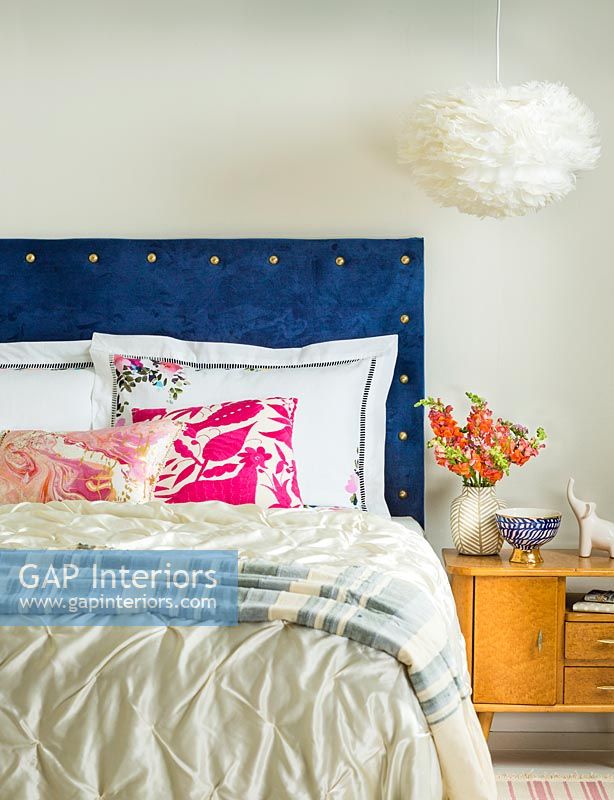 Blue velvet studded headboard in modern bedroom 