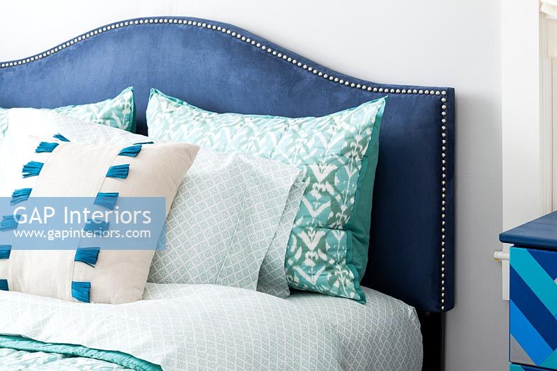 Blue velvet headboard and variety of pillows 