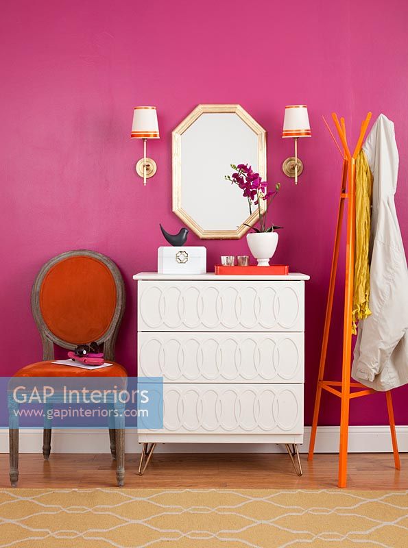 White chest of drawers next to pink painted wall in modern bedroom 