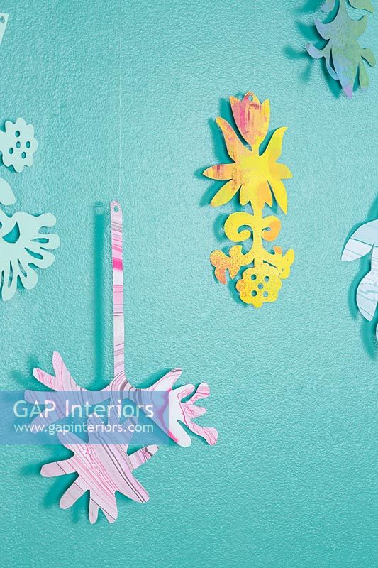 Decorative cutout shapes hanging on painted wall 
