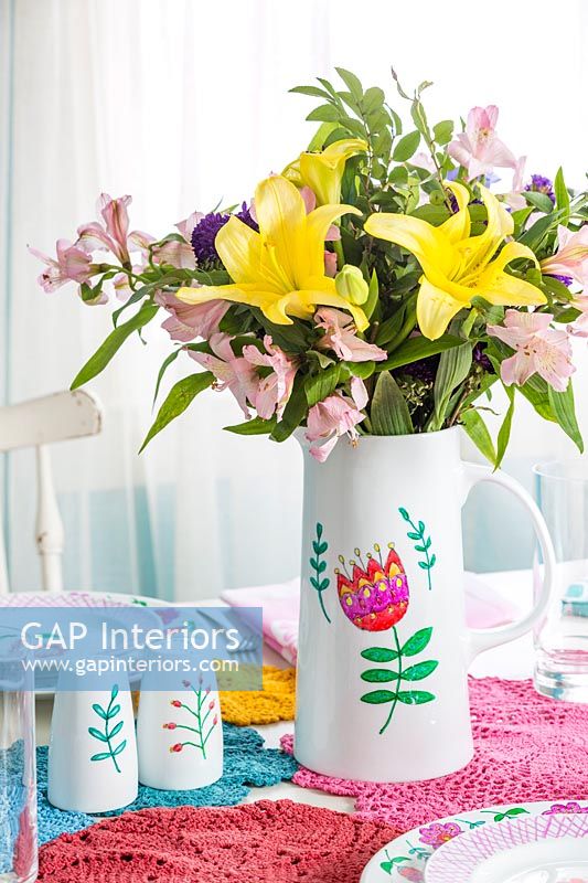 Painted vase of flowers on colourful dining table 