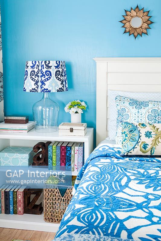 Blue bedroom with white furniture and patterned accessories 