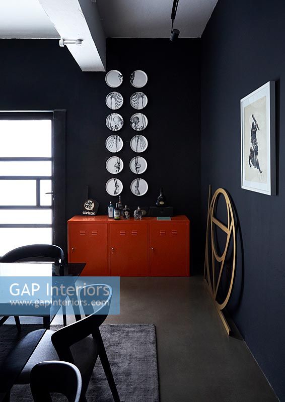 Red sideboard and white wall mounted artwork in black dining room 