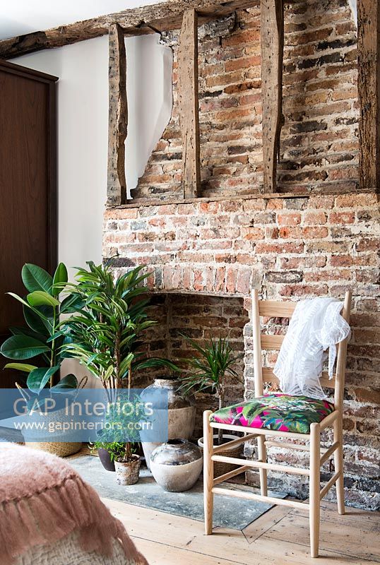 Brick fireplace with exposed beams and houseplants on hearth 