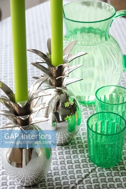 Green glassware and silver novelty candle holders on dining table 
