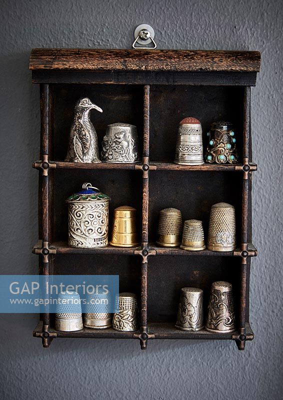 Large collection of thimbles and ornaments displayed on wooden shelves