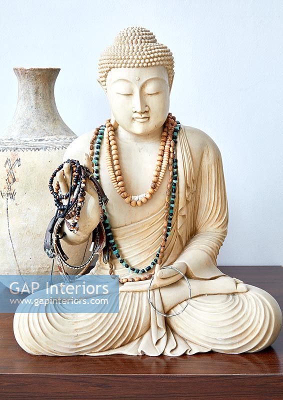 Buddha statuette covered in bead necklaces and bracelets
