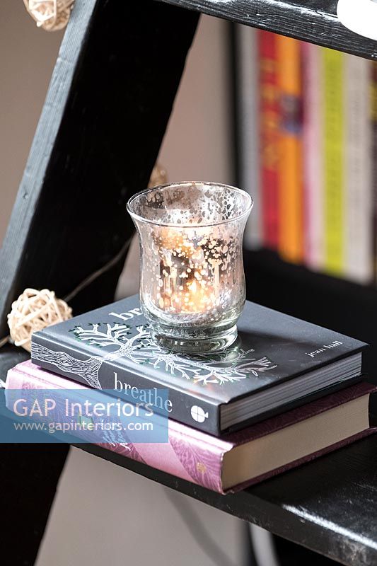 Candle in small glass on top of books 