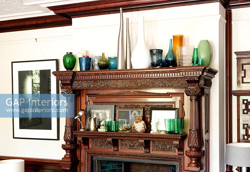 Dark wood fireplace surround displaying glassware and ornaments 