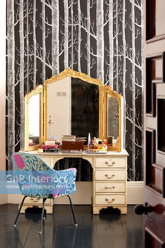 Ornate gilded mirror on dressing table in eclectic bedroom 