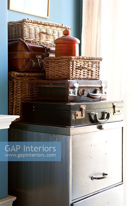 Vintage suitcases and hampers on old metal filing cabinet 