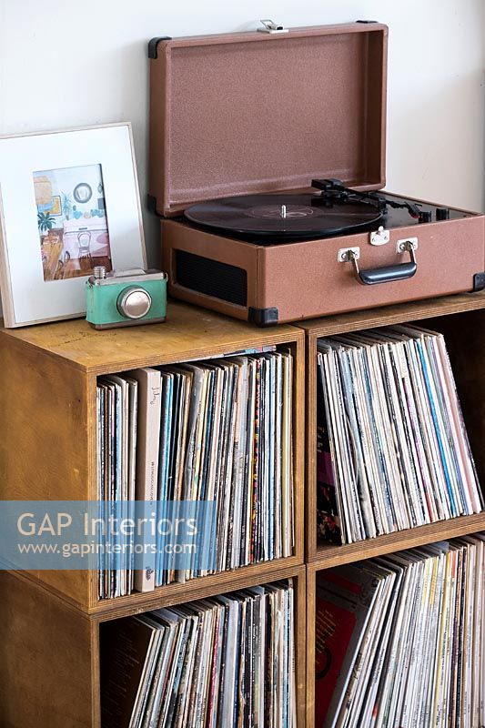 Portable turntable on cabinet filled with vinyl records 
