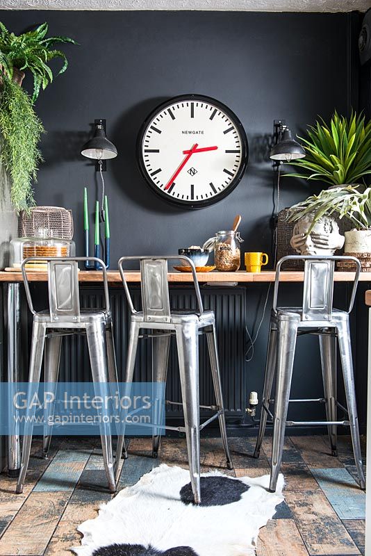 Metal bar stools at breakfast bar with black painted wall