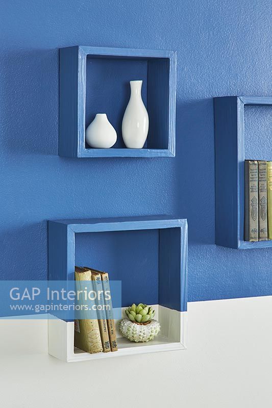 Box shelves on painted wall in half blue half white 