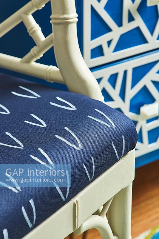Blue and white patterned cushion on painted wooden chair 
