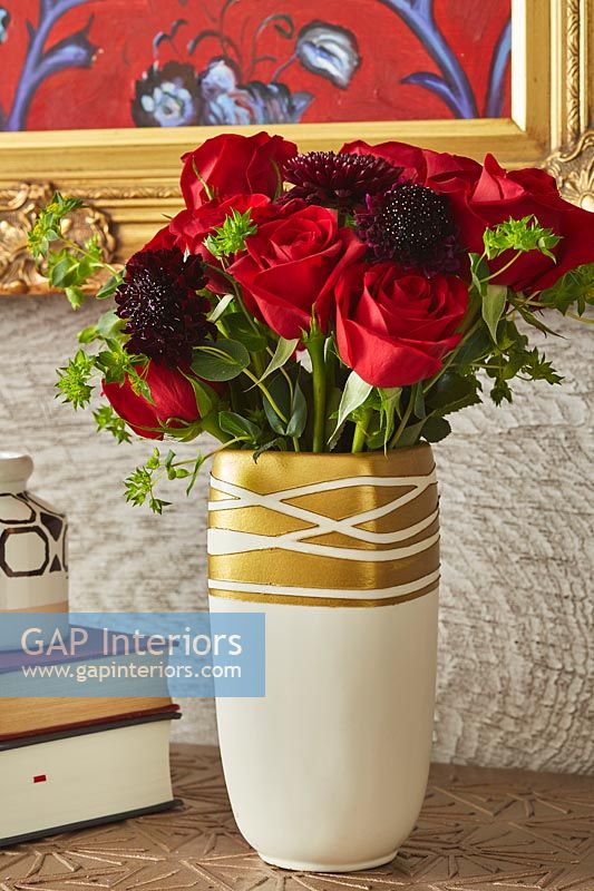 Red roses flowering arrangement in gold vase 