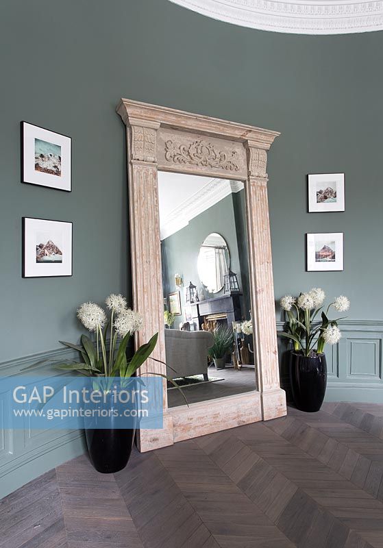 Huge carved mirror against green painted wall
