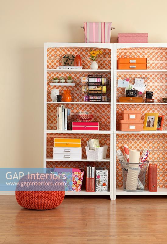 White bookcases backed with orange wallpaper