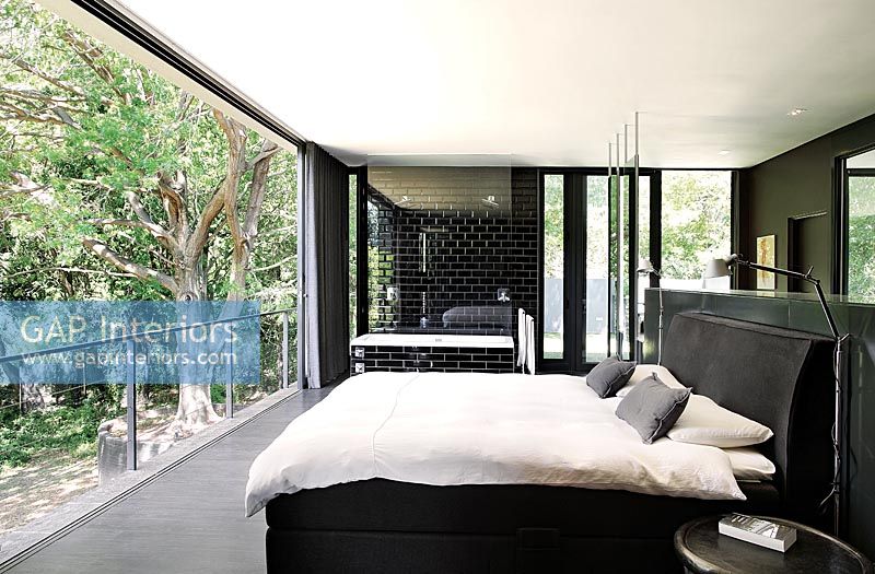 Modern monochrome bedroom with open sliding doors to garden 