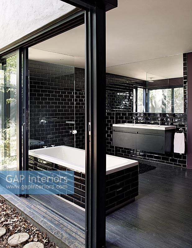 Modern monochrome en-suite bathroom with open sliding doors to garden 