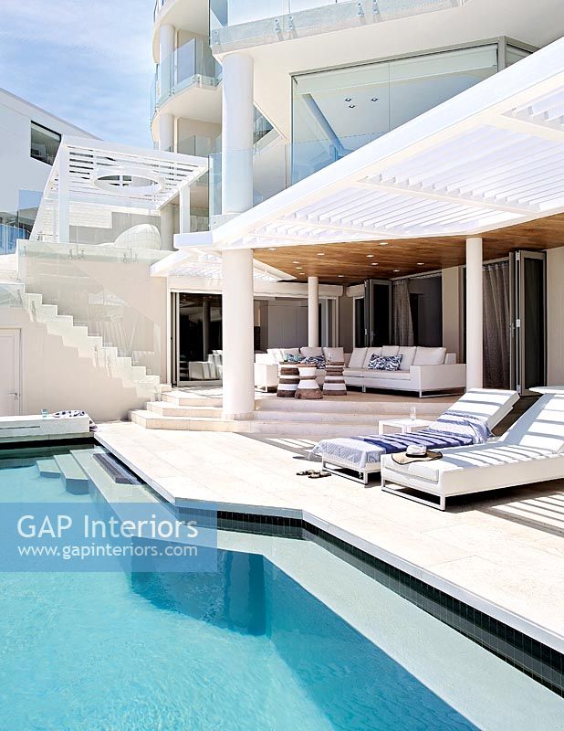 Contemporary house exterior with swimming pool and recliners 