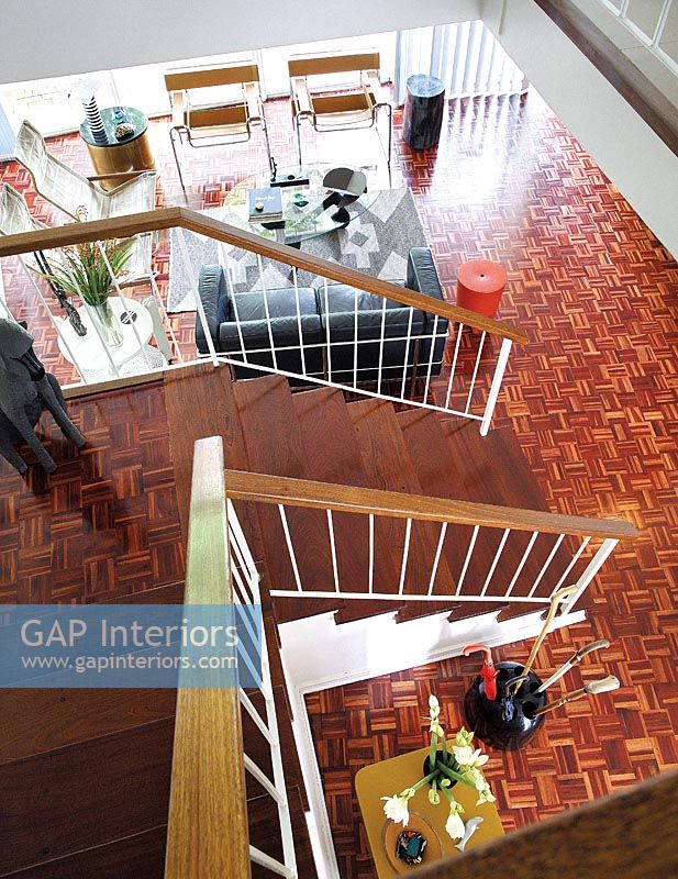 View down modern staircase to open plan living space with parquet floor 