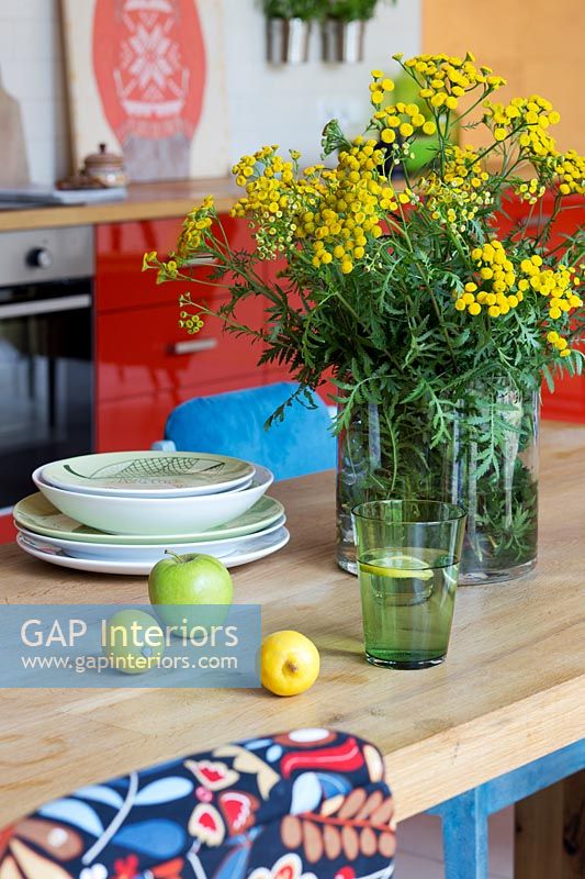 Flowers, fruits and glass on table in kitchen-diner 
