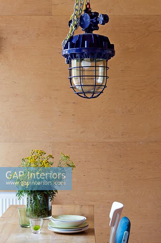 Industrial lamp and flowers in front of plywood wall