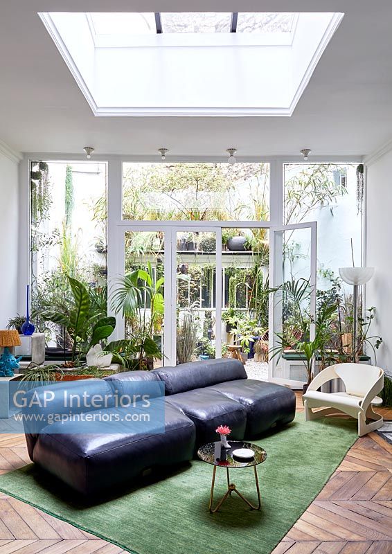 Leather divan sofa in modern living room with view to courtyard garden