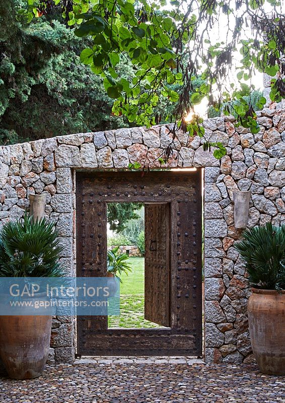 Drystone wall and large studded wooden gateway to garden 