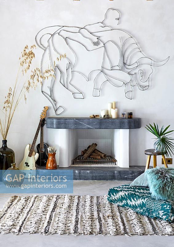 Fireplace with Bull sculpture on wall, guitars and rug 