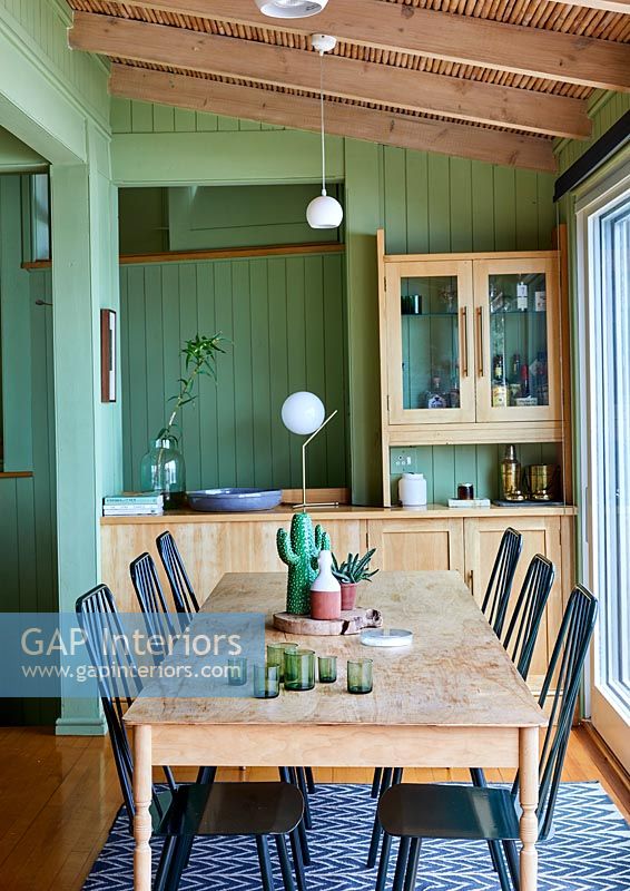 Country dining room with green painted walls and exposed wooden beams 