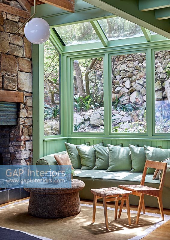Country living room with stone walls and green painted window frames 