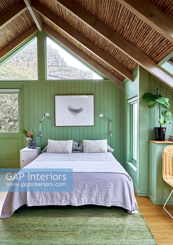 Country bedroom with green painted wooden walls 
