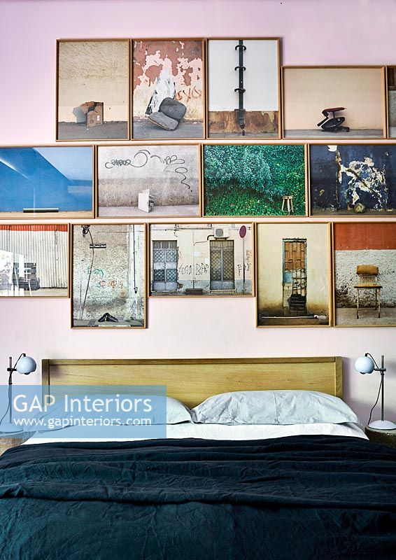 Display of framed photographs over bed in modern bedroom 