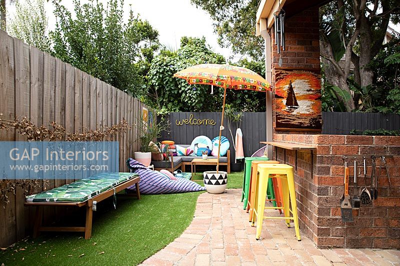 Colourful furniture in garden with brick barbecue area 