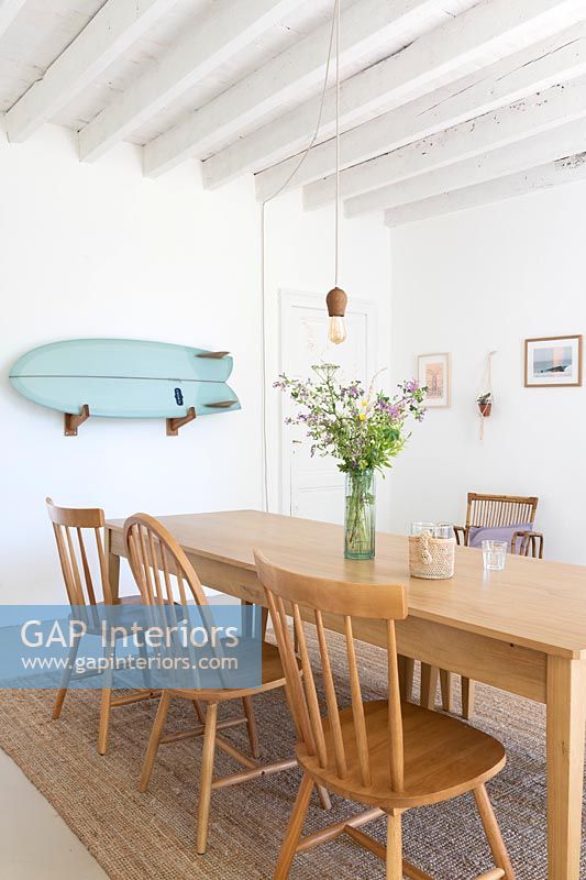 Blue wall mounted surf board on white dining room wall 