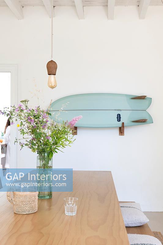 Blue wall mounted surfboard on white country dining room wall 