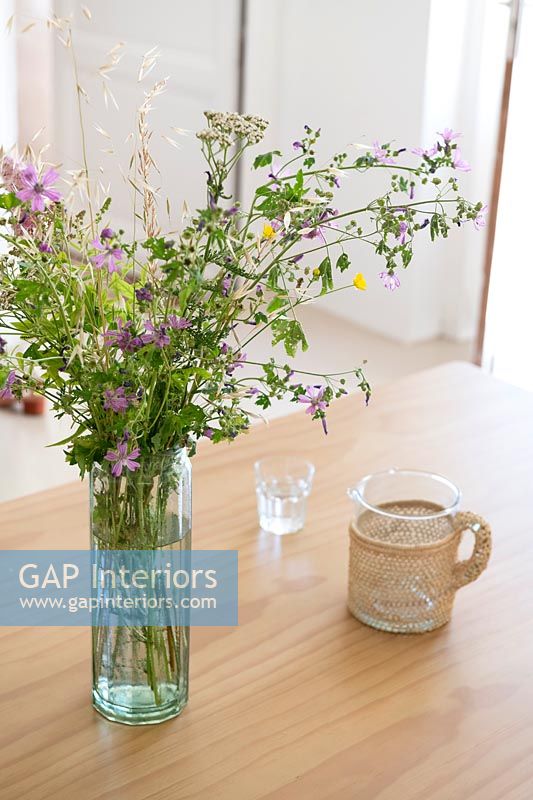 Detail of wildflower arrangement in vase on wooden table 