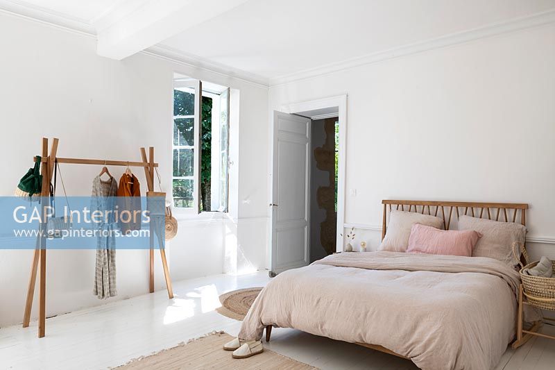 White country bedroom with simple wooden clothes rail 